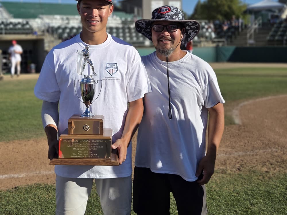 Andrew Ha holding the Northwest Regional championship trophy with his dad at Harry and David Field in Medford.