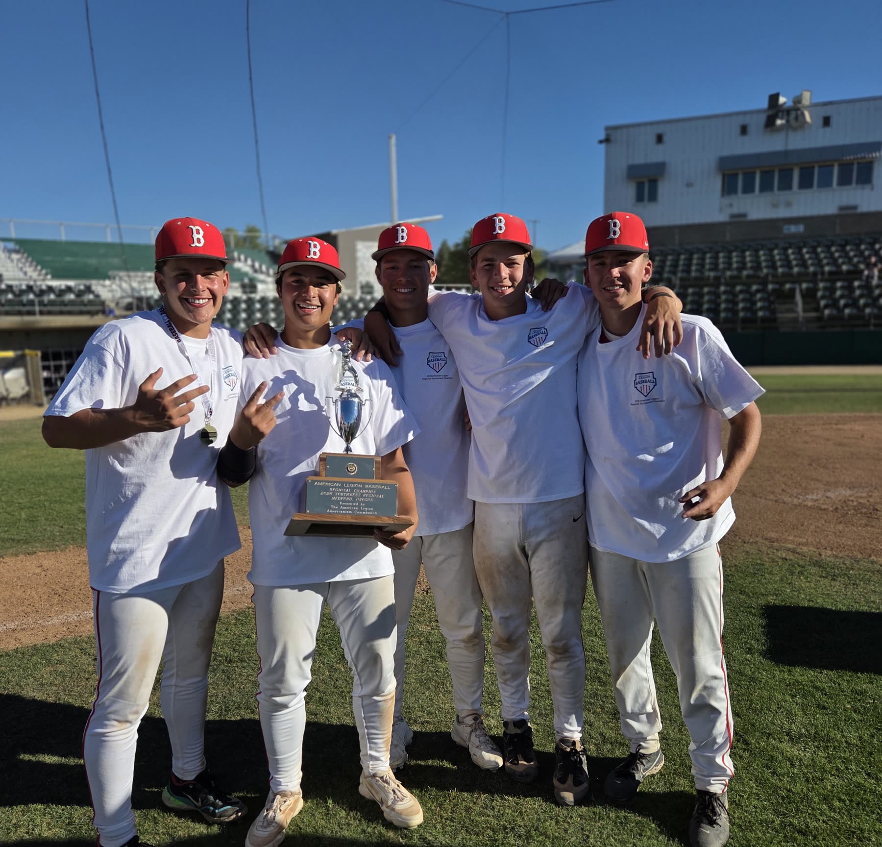 The Post 158 Barbers on the field in Medford with the American Legion Northwest Regional championship banner and trophy.