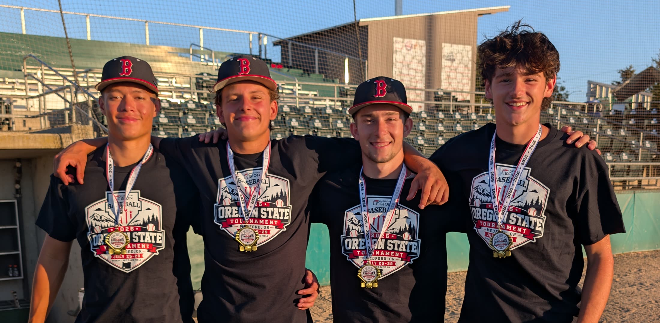 Four Post 158 Barbers players wearing Oregon State Tournament shirts and championship medals after winning the state title in Medford.